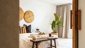 A bedroom with a bed, bedside table, and a potted plant.