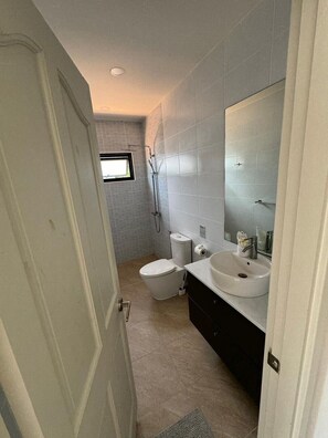A bathroom with a toilet, sink, and shower.