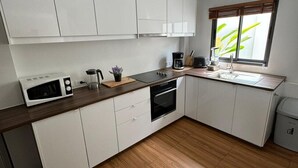 A modern kitchen with white cabinets, a wooden countertop, a built-in oven, a coffee maker, and a window with blinds. - Stylish 2-Bedroom VIlla in Plai Laem, Private Pool with Jacuzzi, Close to Attractions (Koh Samui)