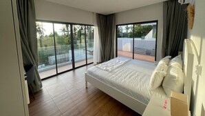 A bedroom with a large bed, a sliding glass door to a balcony, and a white radiator.