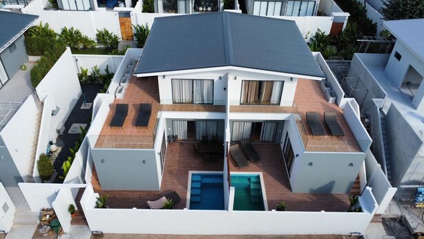 A modern two-story house with a rooftop pool, multiple balconies, and a covered patio area.