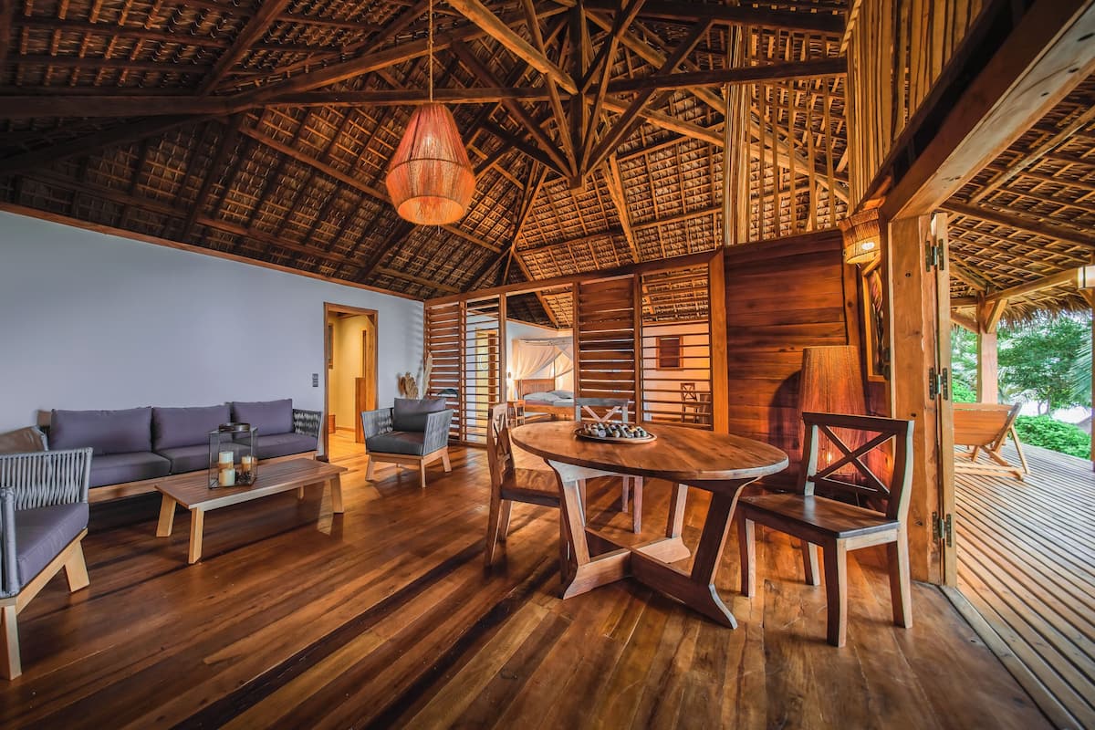 Um quarto espaçoso com teto de madeira, um sofá, uma mesa de jantar e uma cadeira.