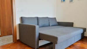 Ein graues Sofa mit Holzboden und Holztür.