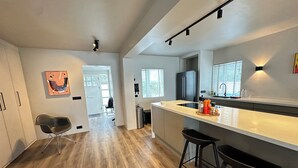 Una cocina moderna con una isla central, taburetes negros y vistas al comedor.
