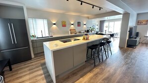 Una cocina moderna con una isla central, electrodomésticos integrados y una zona de comedor con taburetes de bar.