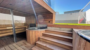 Una terraza de madera con jacuzzis y una pequeña mesa.