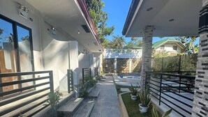 A modern building with a stone pathway, potted plants, and a clear blue sky. - Micasa Mabini (Puerto Princesa)