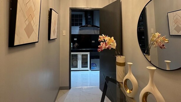 A modern hallway with a chandelier, framed artwork, and a mirror. - Micasa Mabini (Puerto Princesa)
