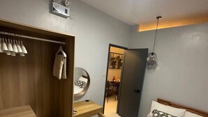 A modern bedroom with a wooden wardrobe, a desk, a bed with patterned pillows, and a ceiling light. - Micasa Mabini (Puerto Princesa)