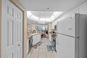 A modern kitchen with white cabinetry, a stainless steel refrigerator, and a skylight above the countertop.