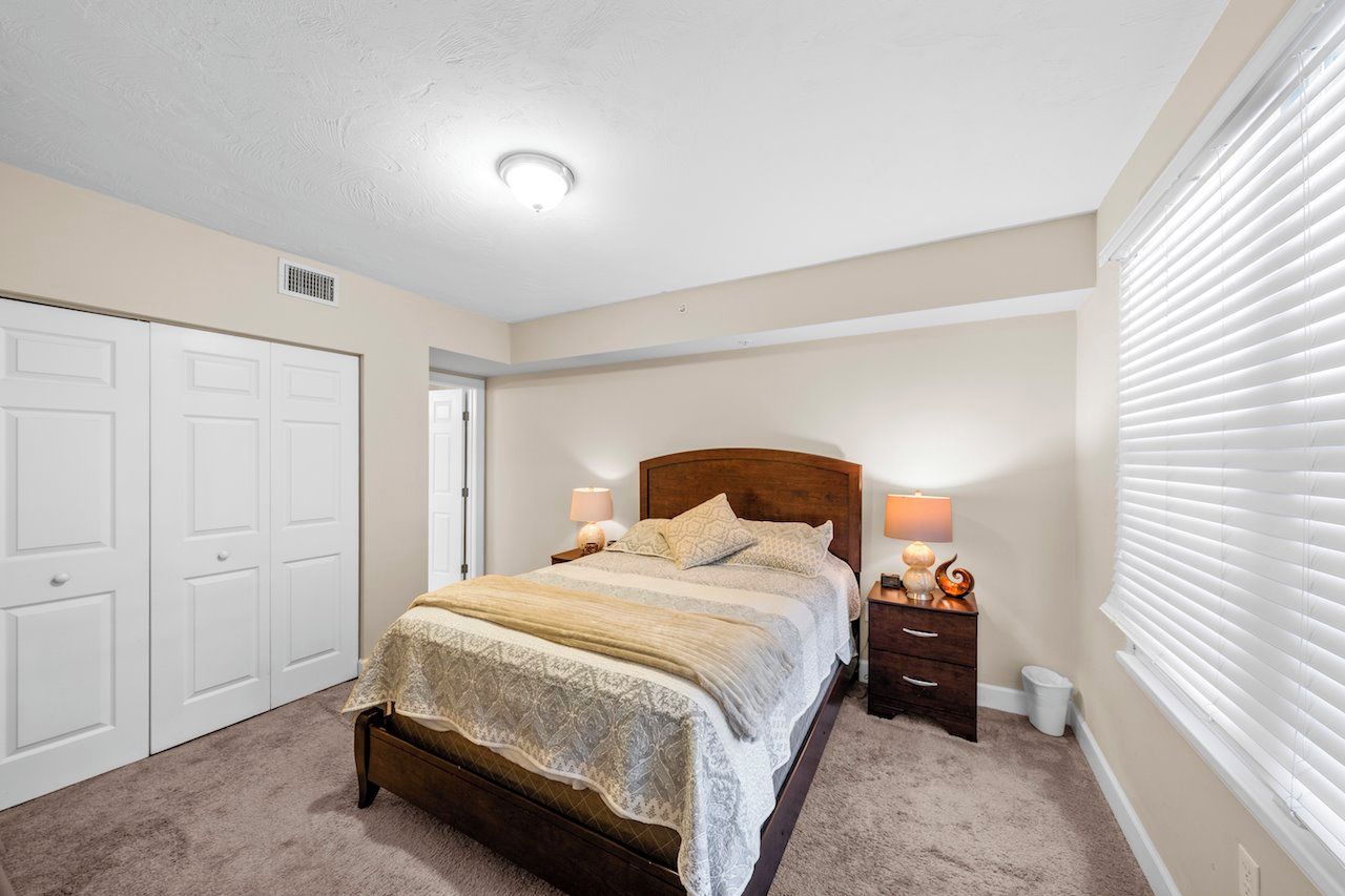 A bedroom with a bed, bedside tables, a wardrobe, and a window with blinds.
