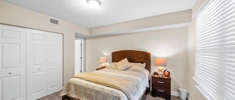 A bedroom with a bed, bedside tables, a wardrobe, and a window with blinds.
