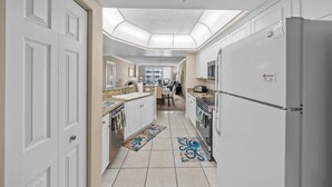 A modern kitchen with white cabinetry, a stainless steel refrigerator, and a skylight above the countertop.