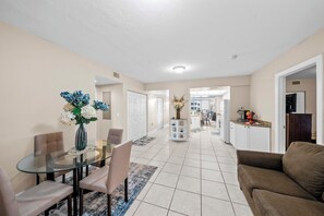 A spacious living area with a glass dining table, beige walls, and a brown sofa. - Towers Grande 301 in Daytona Beach Shores, FL (Daytona Beach Shores)