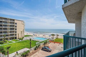 A hotel with a pool, a beach view, and a parking area.