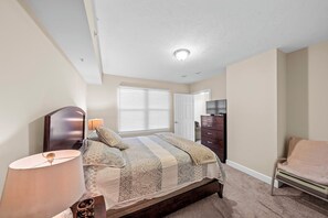 A bedroom with a bed, a dresser, a chair, and a television.