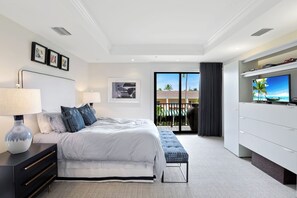 A modern hotel room with a large bed, bedside tables, a TV, and a balcony with a view.