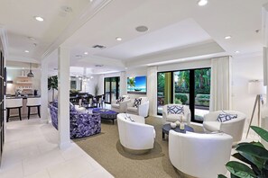 A modern living room with a dining area, large windows, and a view of the outdoors.