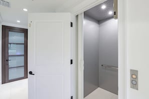 Une salle de bain moderne avec une porte blanche, une douche en verre et un sol carrelé de blanc.