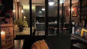 A modern living room with a large window, a dining area with a table and chairs, and a kitchen visible through the window. - Hanoi city center, apartment with all the comforts to visit the city (Hà Nội)