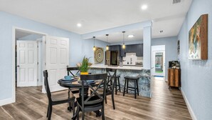 A modern kitchen with a central island, dark wooden chairs, and a dining table set for four.