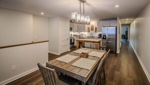 A modern kitchen with wooden flooring, a central island, and stainless steel appliances.