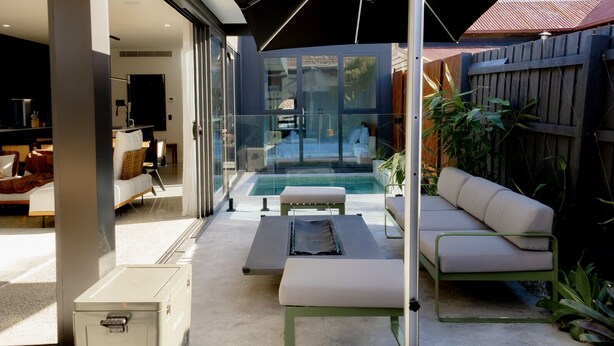 A modern outdoor living space with a pool, glass doors, and a patio area with seating. - Seddon Smart Home with Private Pool Getaway (Seddon)
