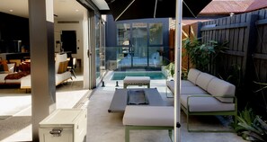 Een moderne buitenruimte met een zwembad, glazen deuren en een patio met zitplaatsen.