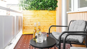 A balcony with a wooden wall, a metal chair, and two bottles of Corona beer on a small round table. - The Romex (Rome)