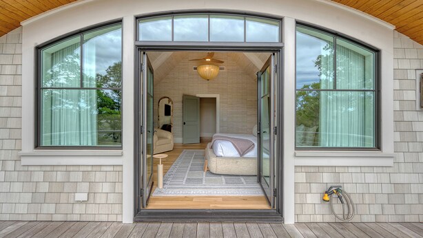Un dormitorio moderno con una cama grande, un ventilador de techo y vistas a través del ventanal.