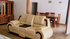 Ein modernes Wohnzimmer mit einem beigefarbenen Ledersofa, einem Holzesstisch und Stühlen.