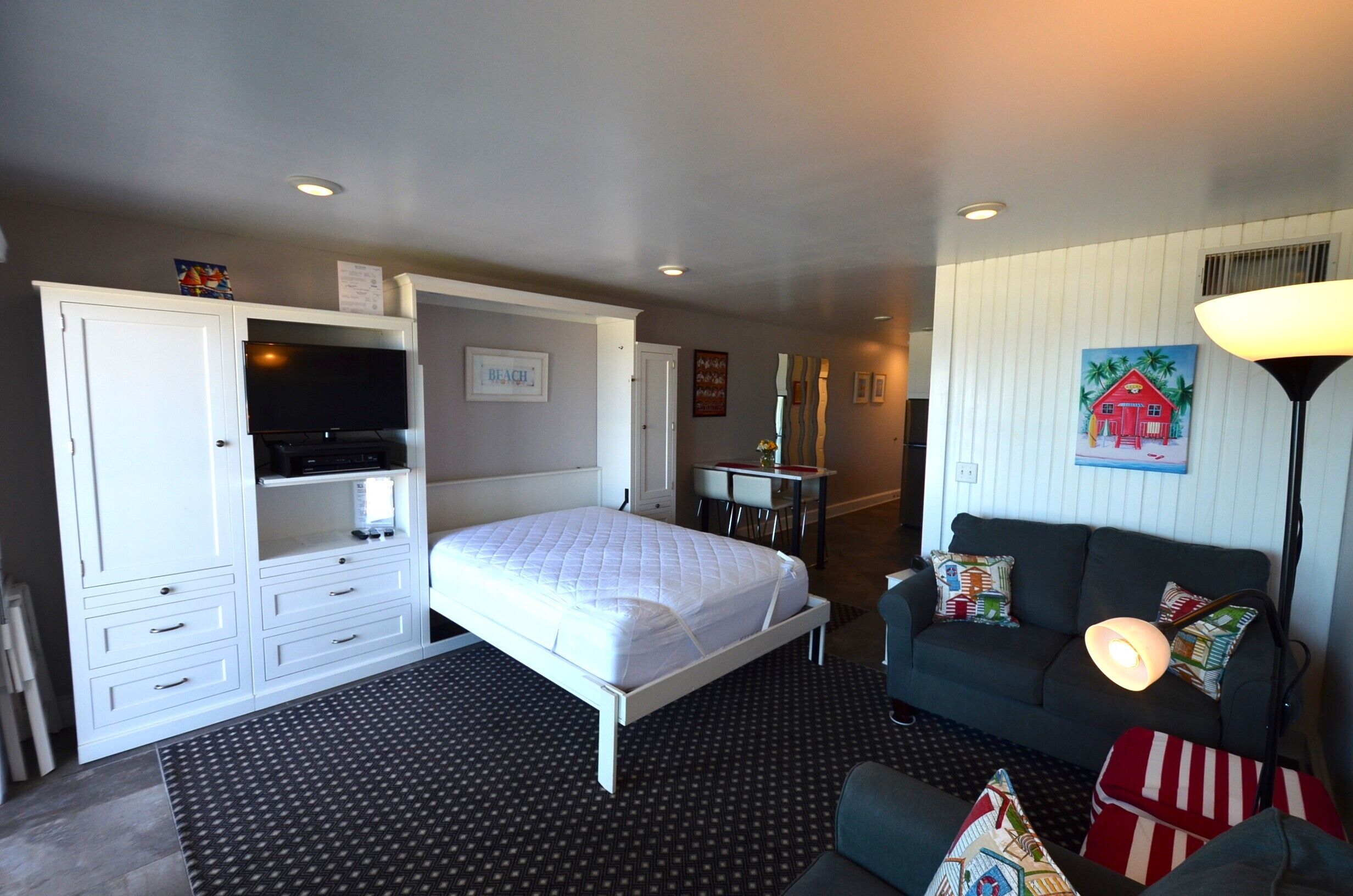 A hotel room with a bed, a desk, a couch, and a TV.