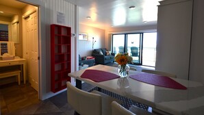 A dining area with a white table, red placemats, and a vase with flowers. - Edgewater House - Ocean Front Units With Spectacular Views! (Rehoboth Beach)
