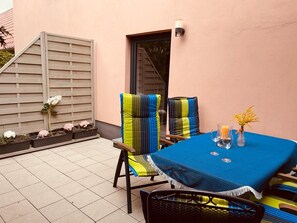 A patio with a table set for two, chairs with striped cushions, a small vase with flowers, and a wall-mounted light fixture. - 5 km from Plau am See: Farmhouse vacation rental with ponies (Barkhagen)