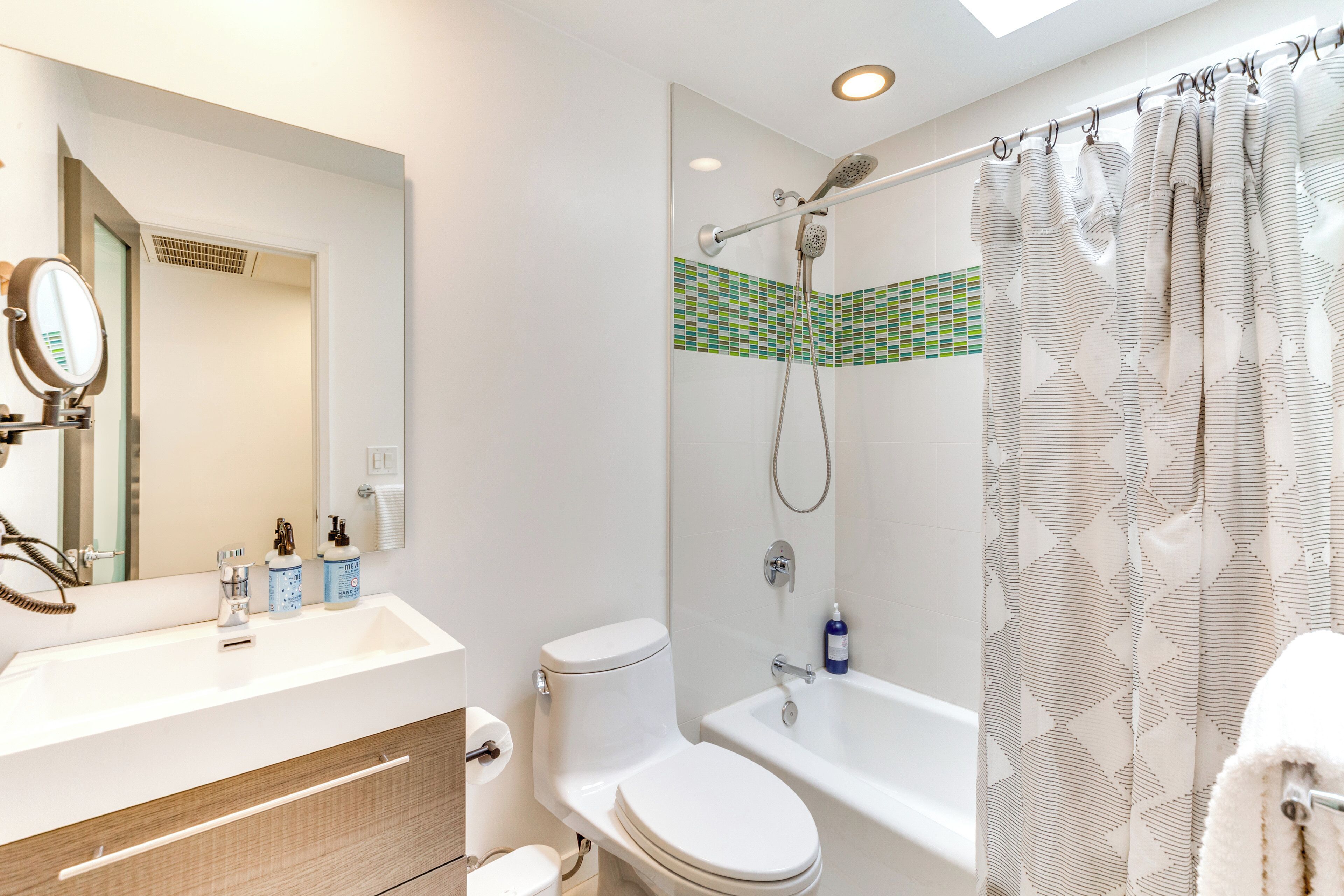 A modern bathroom with a shower, toilet, and sink.