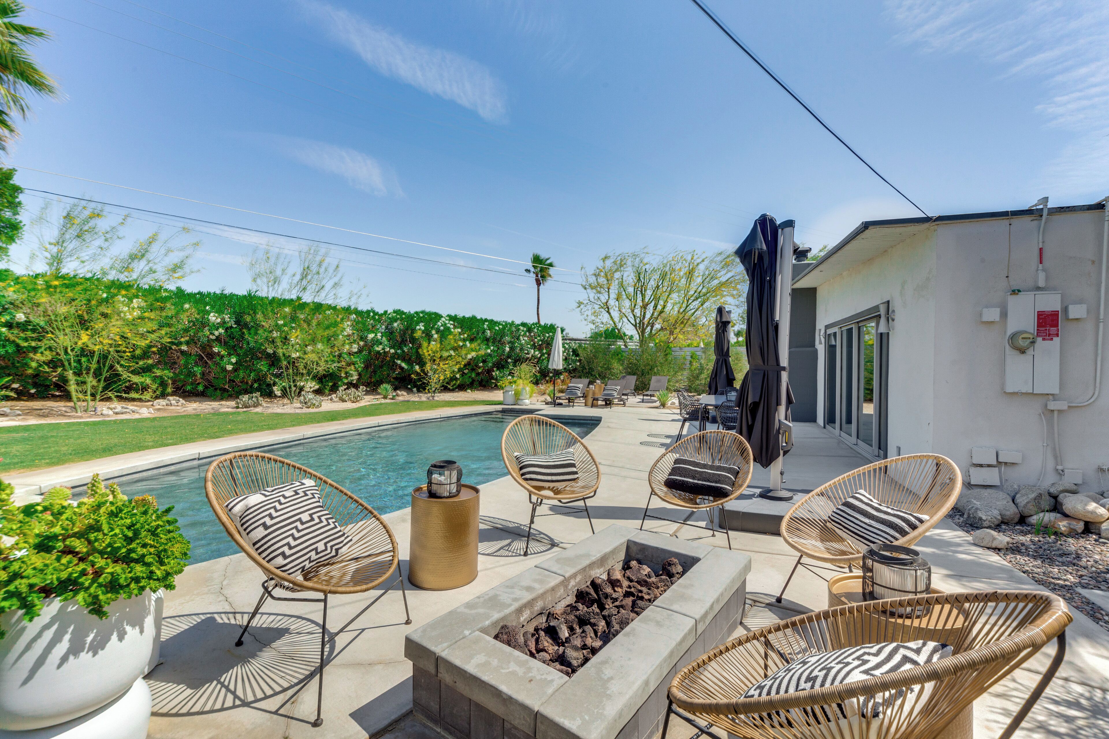 A poolside area with wicker chairs, a fire pit, and a small table.