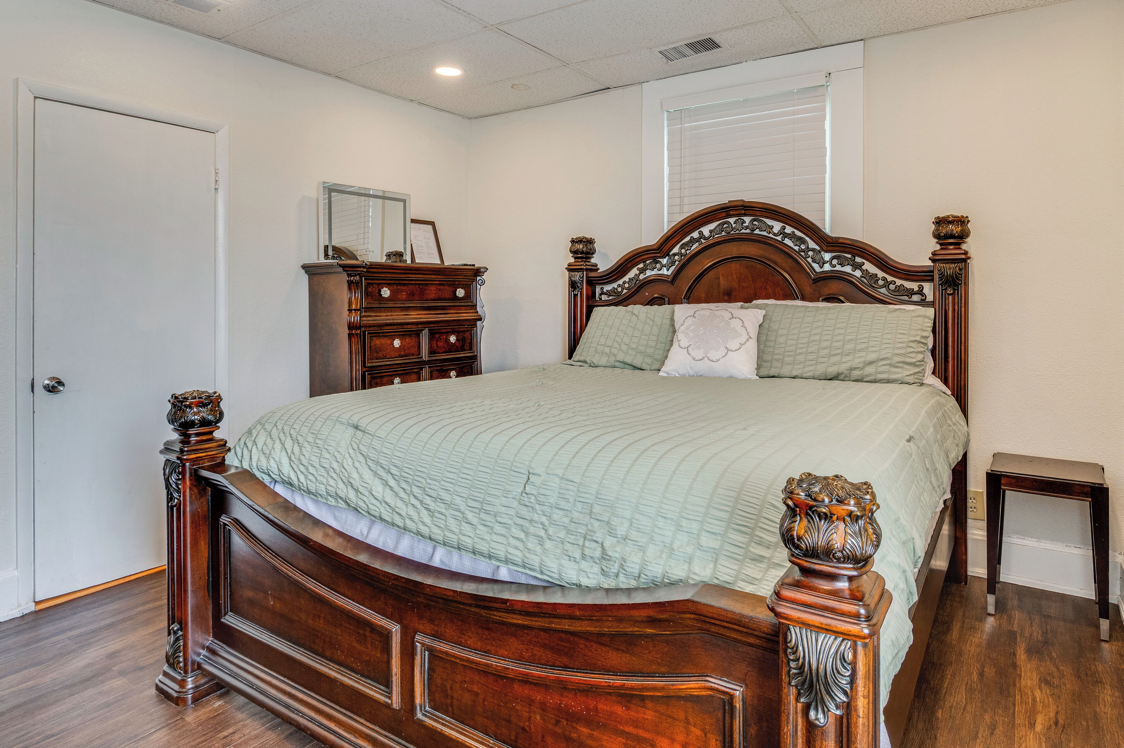 Een slaapkamer met een houten bed, een dressoir en een nachtkastje.