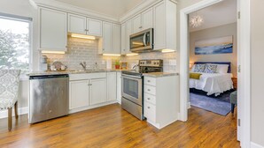 A modern kitchen with white cabinetry, stainless steel appliances, and a large island. - Scenic & Cozy 'sweet Northern Comfort' in Homer! (Homer)