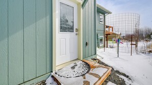 A house with a green exterior, a white door with a window, and a snow-covered porch. - Scenic & Cozy 'sweet Northern Comfort' in Homer! (Homer)