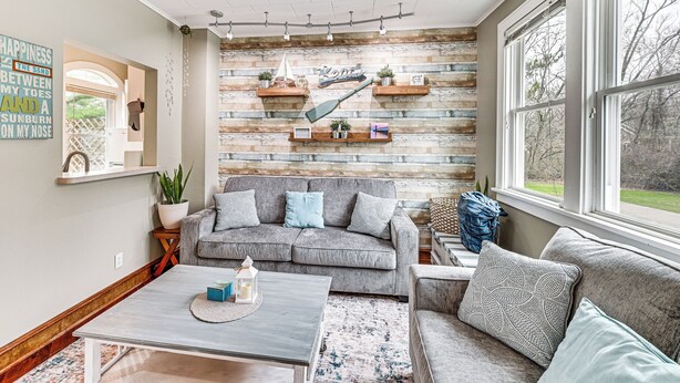 A cozy living room with a gray sofa, a coffee table, and a bookshelf against a wooden wall. - 1/2 Mi to Beach & Lake Michigan: Condo w/ Pool! (South Haven)