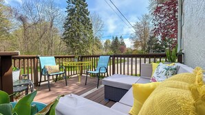 A deck with outdoor furniture, including a sofa and chairs, surrounded by greenery and trees. - 1/2 Mi to Beach & Lake Michigan: Condo w/ Pool! (South Haven)
