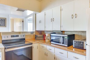 A kitchen with white cabinets, a stove, a microwave, a toaster, and a coffee maker. - Historic Manor 3 Mi to Shawnee Mtn! Pet Friendly (East Stroudsburg)