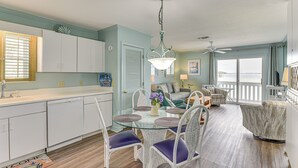 A spacious living area with a glass dining table, white wicker chairs, and a view of the ocean. - Family-friendly Fort Walton Beach Condo w/ Views (Fort Walton Beach)