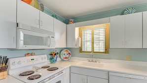 A kitchen with white cabinets, a microwave, stove, and a sink. - Family-friendly Fort Walton Beach Condo w/ Views (Fort Walton Beach)