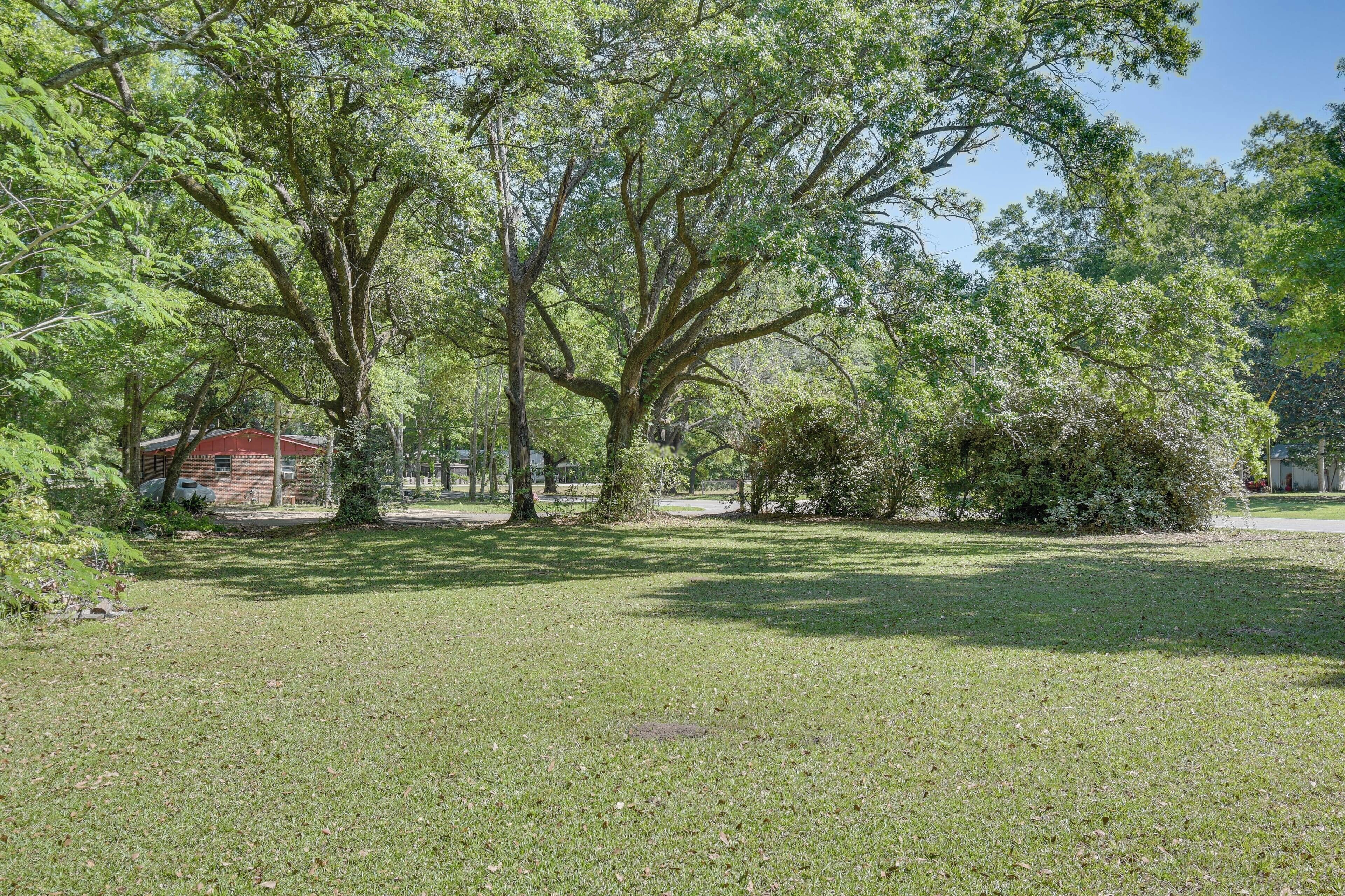 A grassy area with trees and a red building.