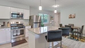 A modern kitchen with stainless steel appliances, a granite countertop, and a central island with bar stools. - 11 Mi to Beaches: Peaceful Foley Home w/ Yard (Foley)