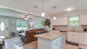A spacious living room with a brown leather sofa, a dining area, and a kitchen with white cabinets and granite countertops. - 11 Mi to Beaches: Peaceful Foley Home w/ Yard (Foley)