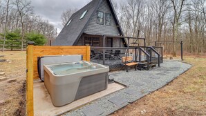 Ein gemütliches Blockhaus mit Whirlpool, einer Holzterrasse und einer Treppe zu einer Veranda.