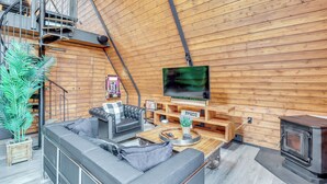 Ein gemütliches Wohnzimmer mit Sofa, Couchtisch, Fernseher und Kaminofen.