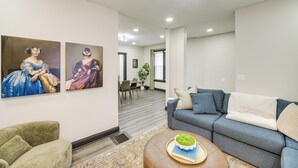 A modern living room with a grey sofa, a green armchair, and two paintings on the wall. - 4 Mi to Dtwn: Modern Retreat w/ Yard in Cleveland (Cleveland)